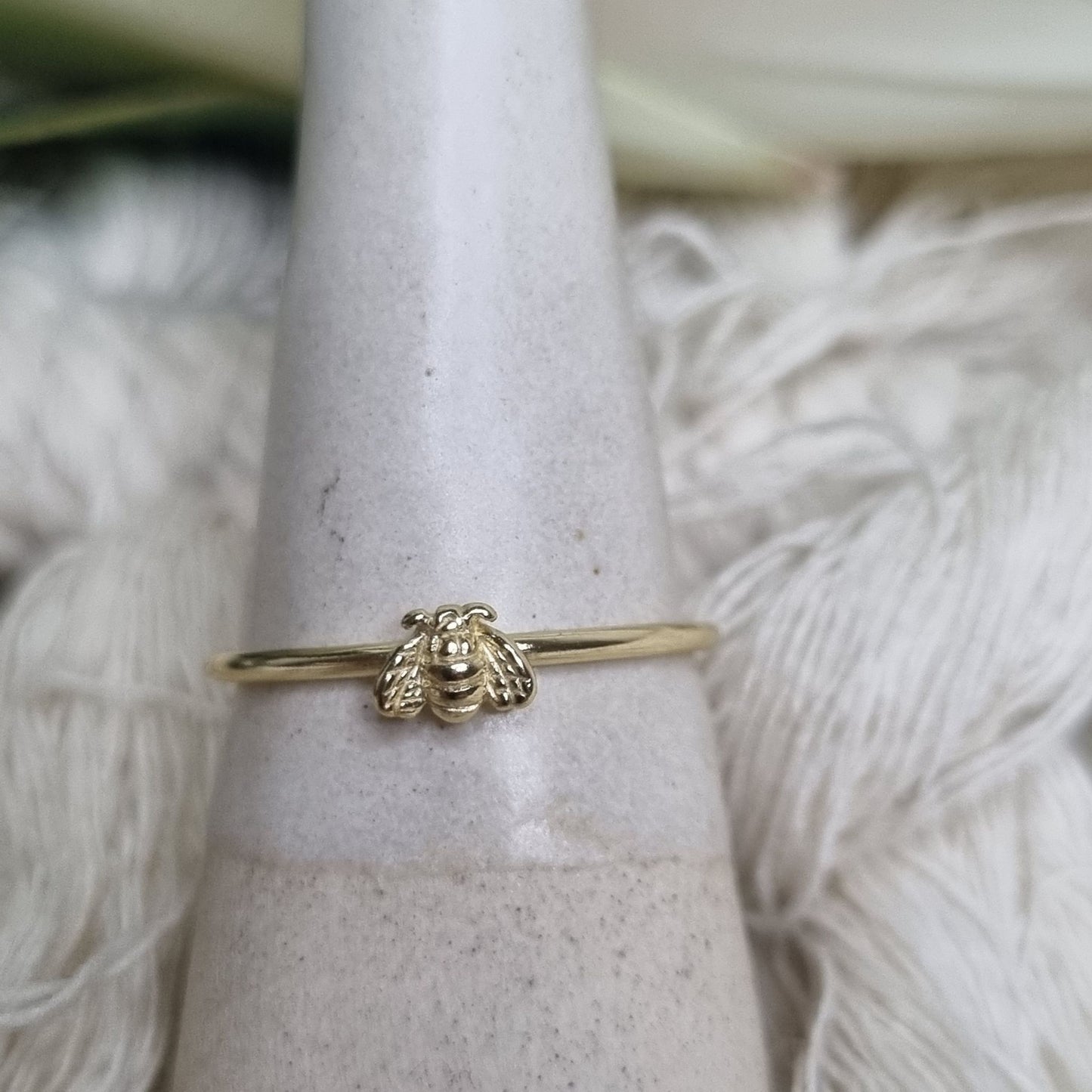 Delicate gold ring with detailed bee charm from side angle