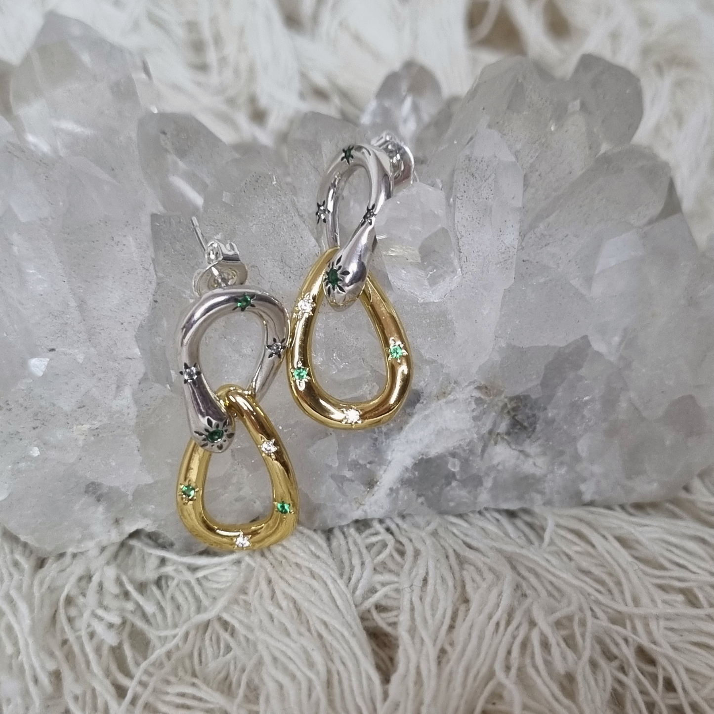 Gold and silver earrings on a crystal background