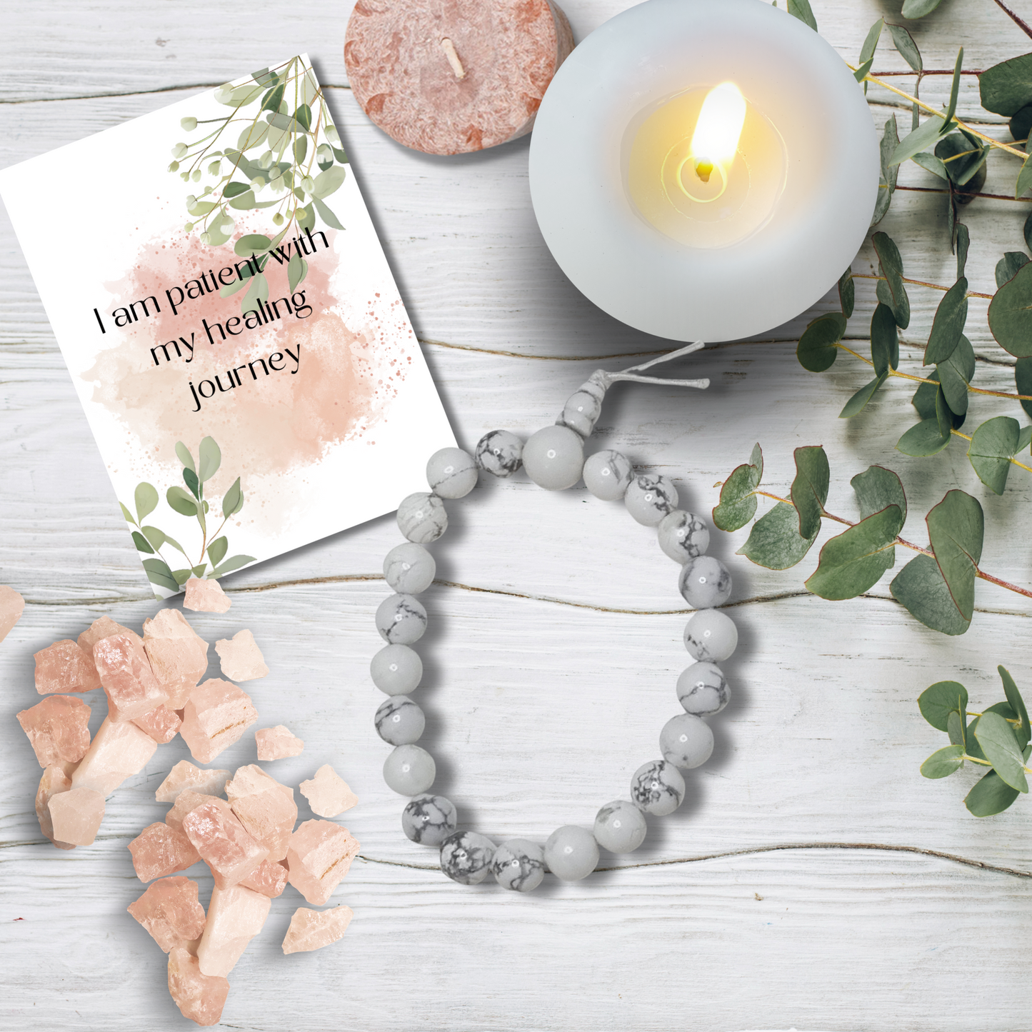 Gray beaded bracelet on a wooden surface with a candle, card, and crystals.White Howlite Tumblestone Bracelet