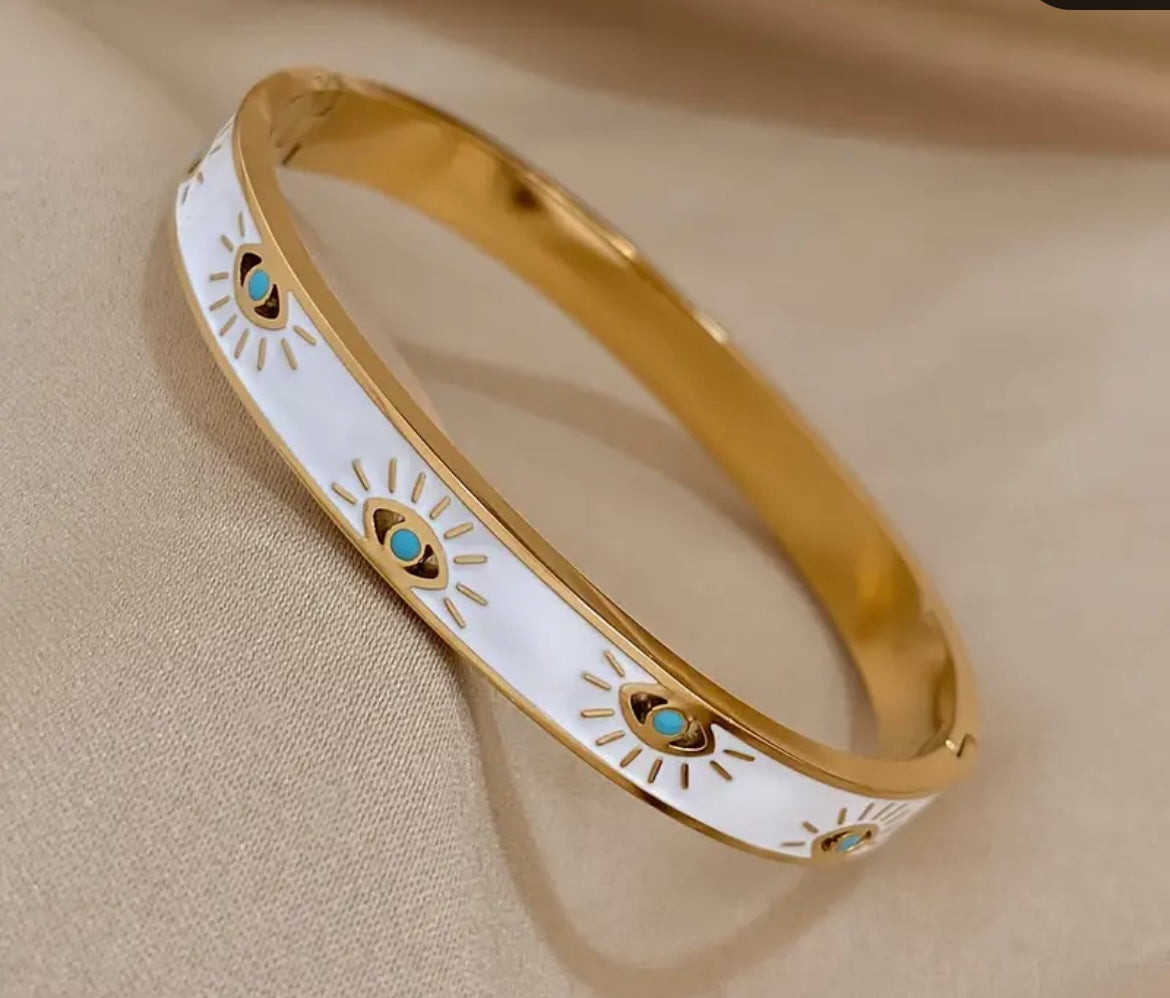 Add symbolic style to your stack with this 18K Gold Evil Eye Bangle, crafted from durable stainless steel and designed to offer both meaning and everyday wearability. The intricate evil eye motif represents protection and positivity, guarding against negative energy while adding a polished finish to your look.