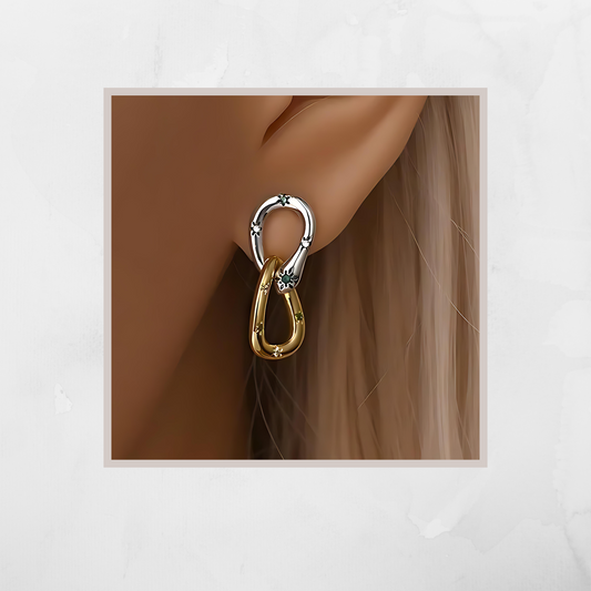 Gold and silver earring worn on an ear with a neutral background