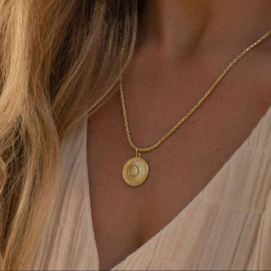 Embrace the light with our Sun Soul Necklace, inspired by the beauty of sun-drenched days, coastal freedom, and soulful connection to nature. This signature piece features a finely detailed golden medallion suspended from a textured rope-style chain, offering both warmth and elegance in every detail.