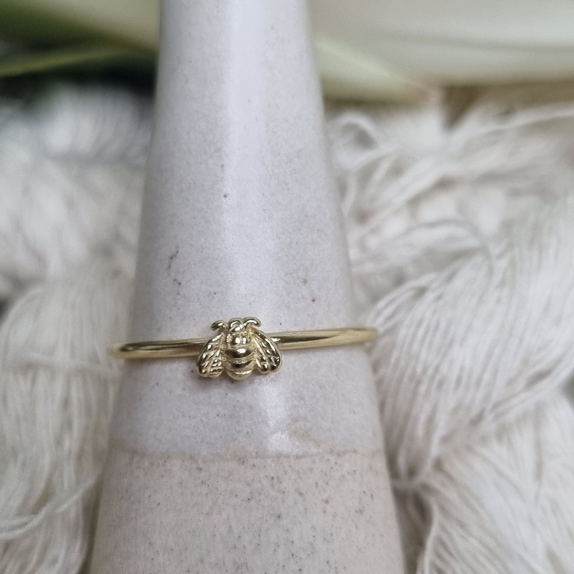 Delicate gold ring with detailed bee charm from side angle