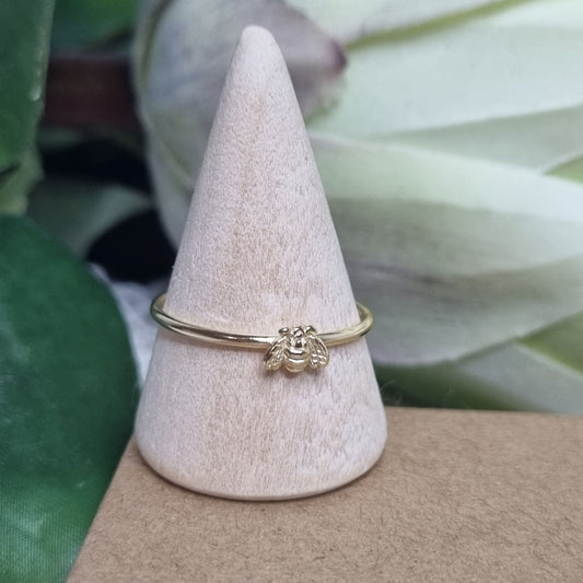 Gold bee ring stacked with other minimalist rings