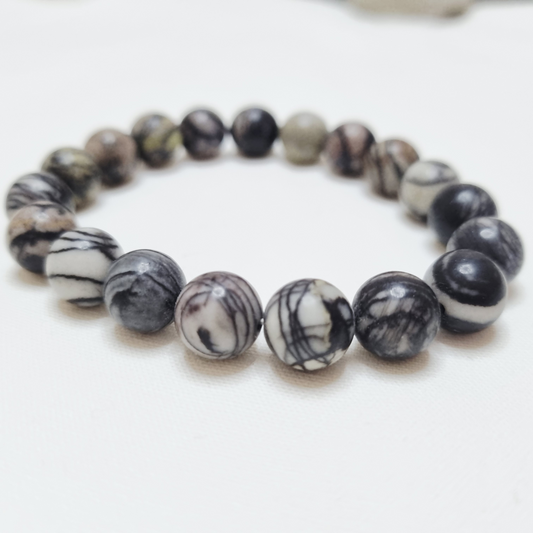 Black and white marbled bead bracelet on a white background.Natural Black Web Jasper