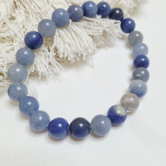 Beaded bracelet with blue and gray beads on a white fabric background.Natural Blue Aventurine