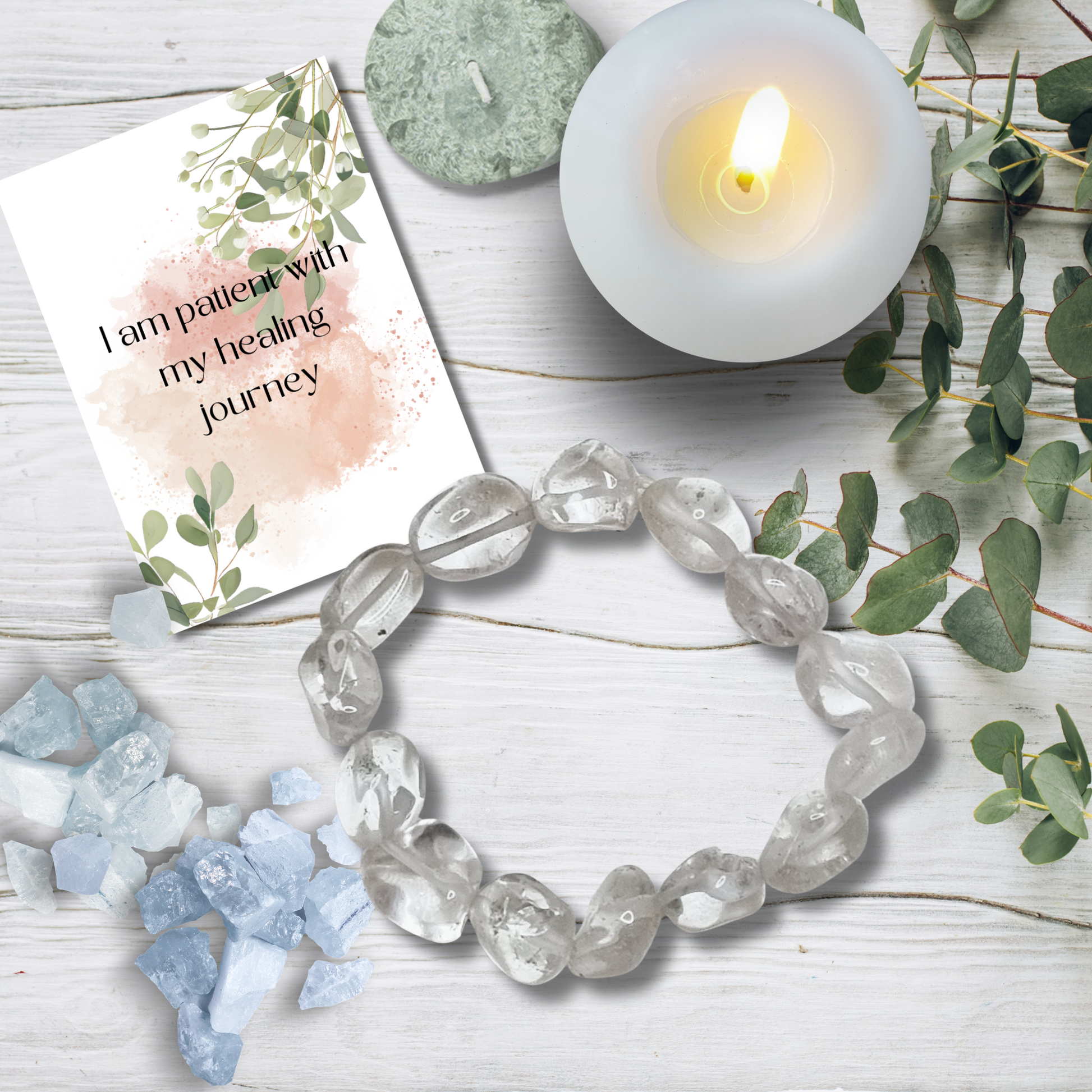 Crystal bracelet on a wooden surface with a lit candle and a card reading 'I am patient with my healing journey'.