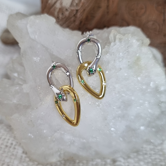 Pair of gold and silver earrings with green gemstones on a textured white surface.