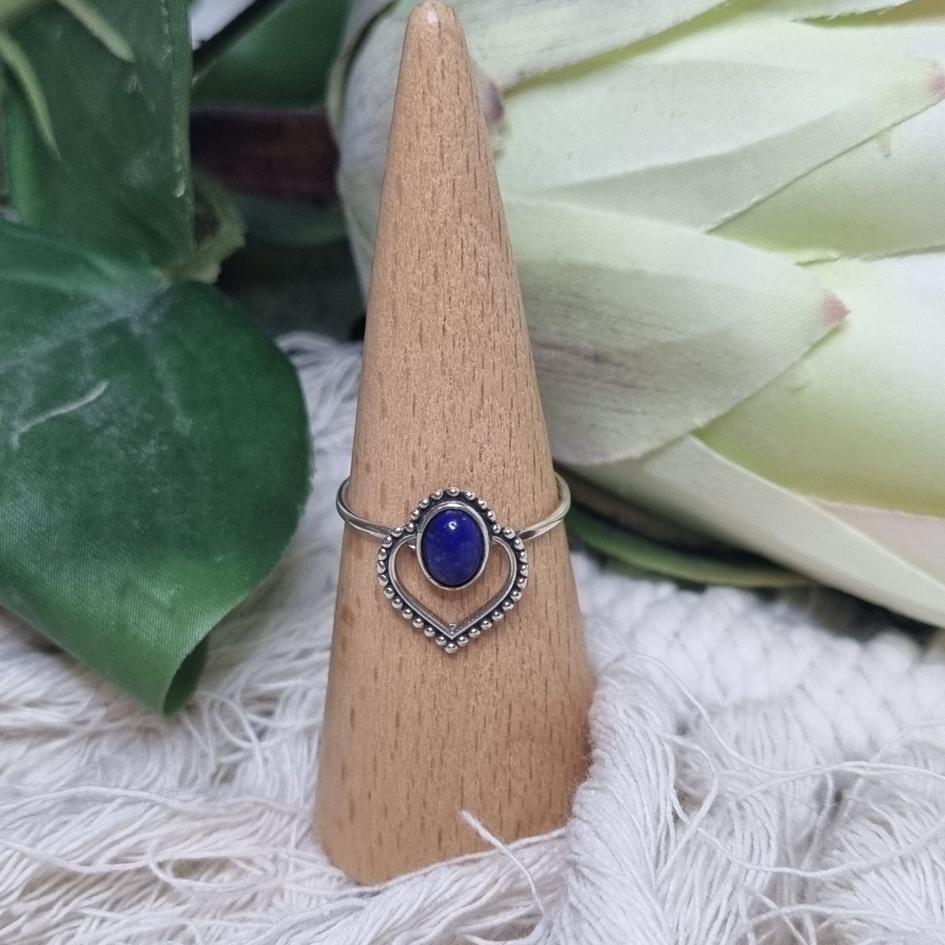 Front view of sterling silver ring featuring oval lapis lazuli stone set in a beaded heart frame