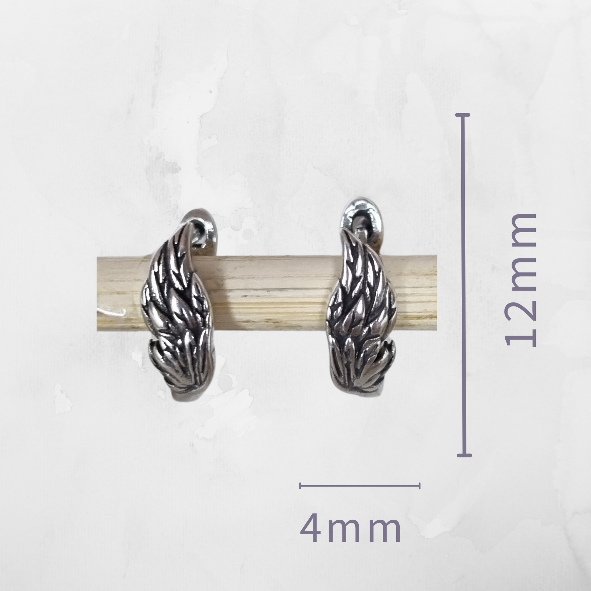 Silver earrings with measurements on a white background