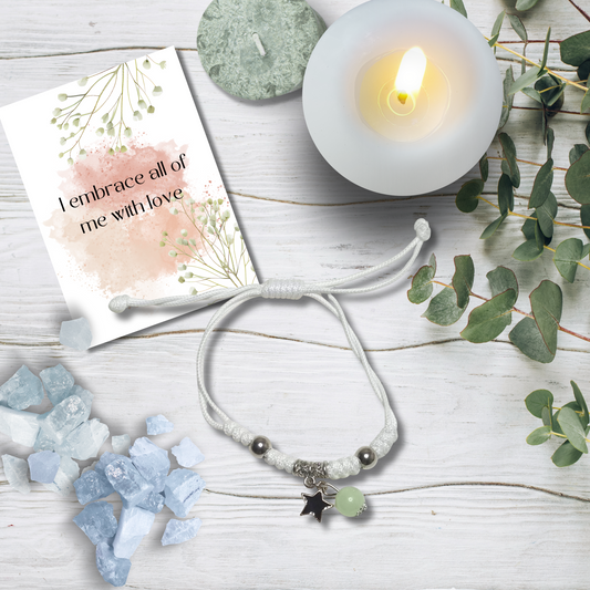 Bracelet with charms on a wooden surface with a candle and card