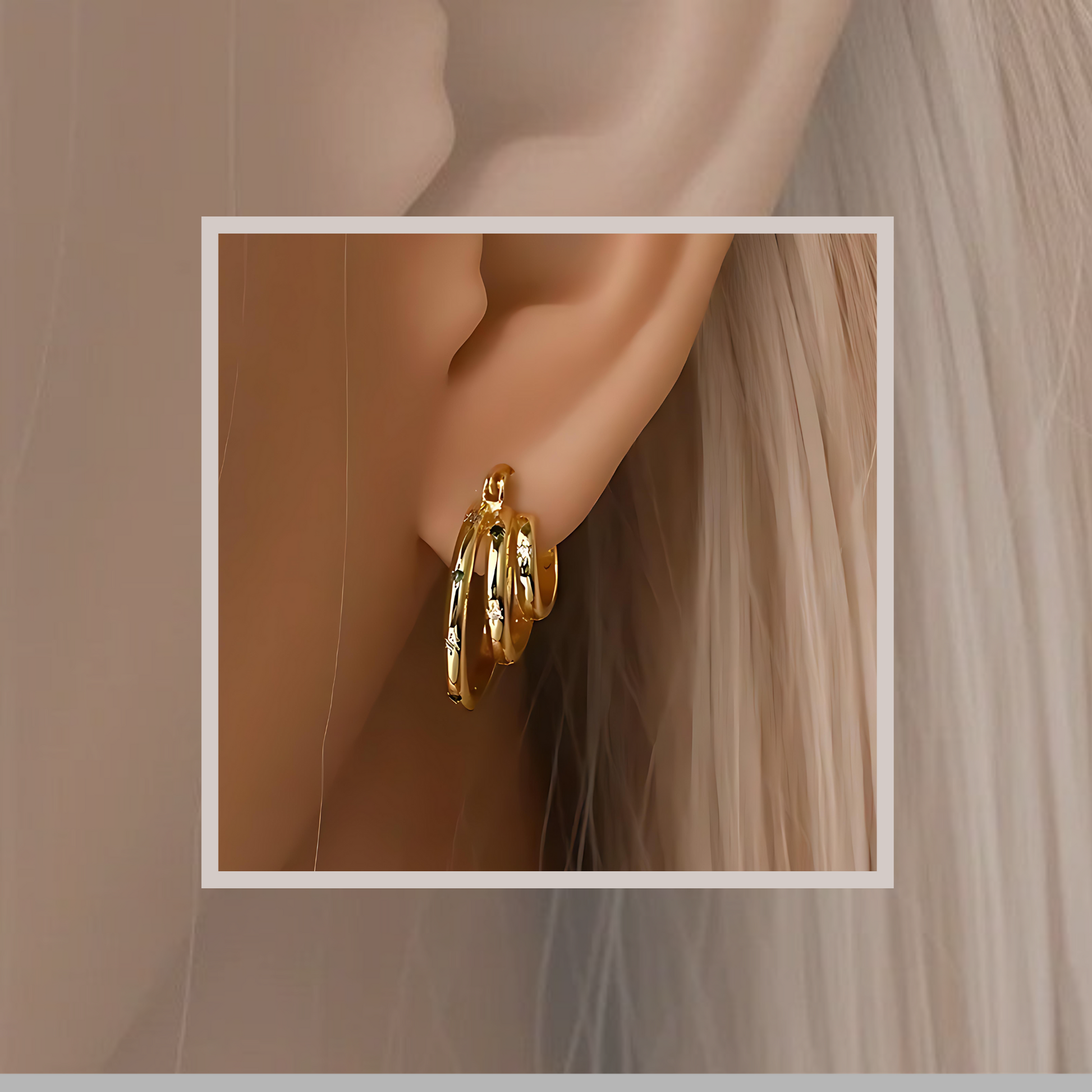 Gold-plated sterling silver stacked hoop earrings worn on an ear, showing the layered design and sparkle of emerald and CZ stones.